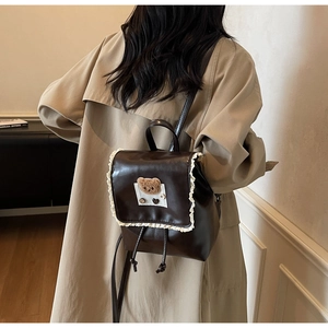 Detail view of brown PU leather backpack with cute lace trim and plush bear decoration