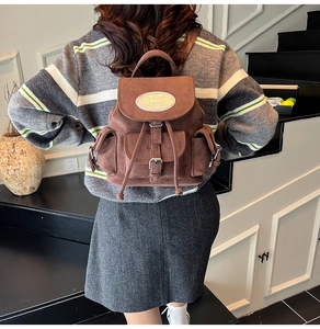 Vue détaillée du mini sac à dos en daim marron foncé avec boucles métalliques et rabat