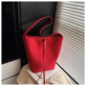 Close-up of red suede bucket bag with leather drawstring detail on art books