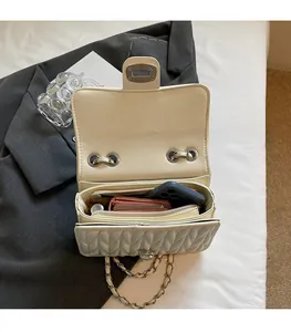 Detailansicht der geräumigen Innenfächer der gesteppten beigen Kettenschultertasche
