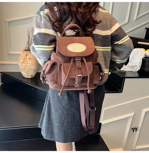 Gros plan du sac à dos en daim marron avec cordon et boucle métallique vintage