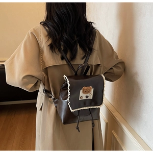 Detail of vintage brown PU leather backpack with lace trim and plush bear patch decoration