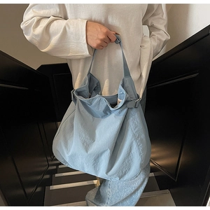 Detail of light blue slouchy tote bag with nylon texture and metal buckle on strap