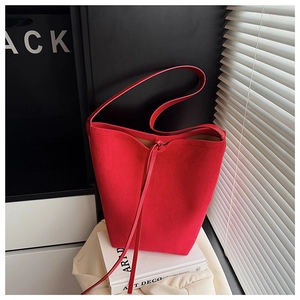 Detail view of the red suede bucket bag showing fine material texture and tassel drawstring