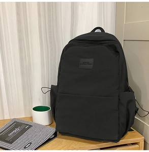 Close-up of black waterproof nylon backpack featuring leather logo and side drawstring pocket