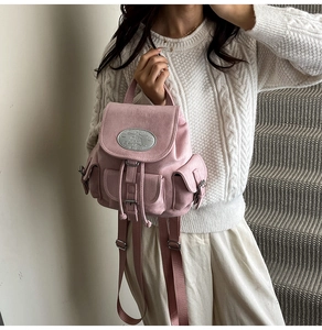 Sac à dos rose minimaliste avec plusieurs poches et une plaque de logo en métal poli