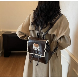 Detail of coffee brown backpack with white lace edges and cute bear embroidery patch