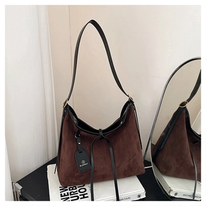 Detail of dark brown faux suede tote bag with black leather trim and brand logo tag