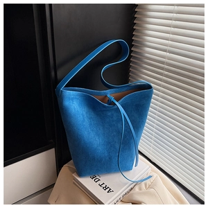 Detail of royal blue suede bucket bag with drawstring closure and soft shadow effects