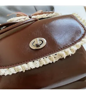 Detail of dark brown faux leather backpack with lace trim and silver twist lock
