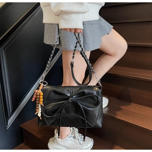Detail of black leather shoulder bag with a large bow and colorful beaded charm