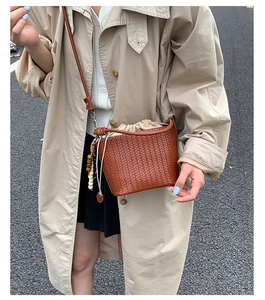 Detail of hand-woven brown bucket bag with canvas drawstring pouch and wooden bead tassel