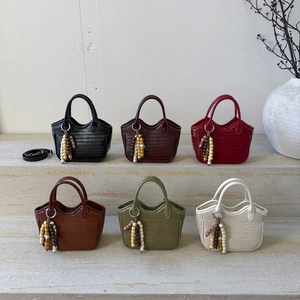 Mini woven bucket bags in six colors with wooden bead charms on stone steps