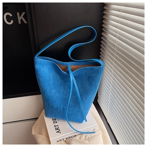 Detailed view of the bright blue suede bucket bag with drawstring and textured leather