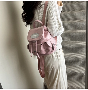 Détail d'un mini sac à dos en daim rose avec cordon de serrage et plaque argentée