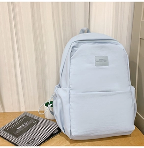 Detail view of water-resistant light blue nylon backpack with branded square leather logo