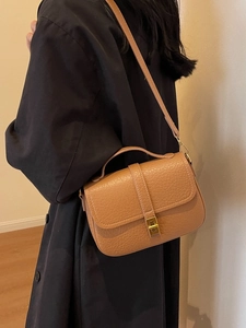 Retro brown litchi leather crossbody bag with gold metal lock worn by a model