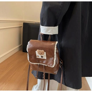 Detailed view of brown lace-trimmed backpack with a cute plush bear and high-quality leather