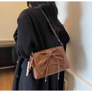 Bolso bandolera retro marrón con lazo decorativo y colgante de cuentas en modelo