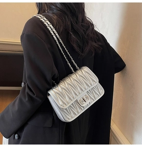 Detailsicht der silbernen Stepptasche mit Kettenriemen und Metallverschluss am Model