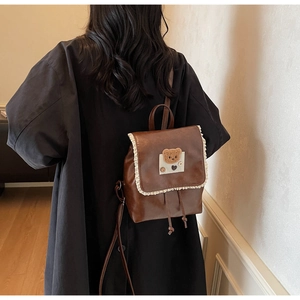 Close-up of brown PU leather backpack with lace trim and cute bear embroidery patch