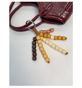 Vue détaillée d'une breloque en perles de bois bohème sur un sac seau tressé bordeaux