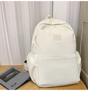 Detailed close-up of white large capacity backpack with front pocket on wooden table