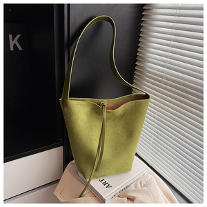 Close-up of olive green suede bucket bag with drawstring detail and slim shoulder strap