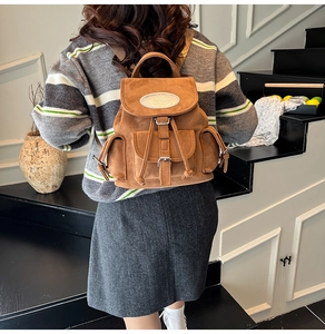 Vue détaillée du sac à dos en daim marron avec une plaque logo en métal argenté élégante