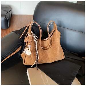 Gros plan sur un cabas en daim marron avec breloque Coffee et détails de couture cuir