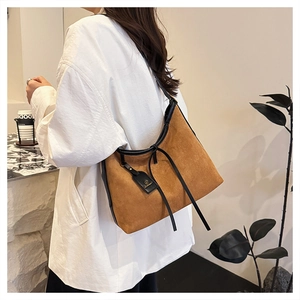 Close-up of brown suede tote bag featuring black leather trim and long tassel drawstring