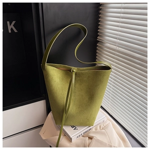 Detailed close-up of lime green suede bucket bag with leather drawstring and matte finish