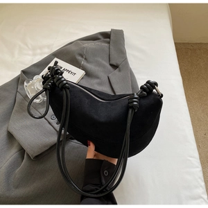 Close-up of black crescent shoulder bag with knot detail and silver zipper