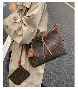 Braune Monogramm-Einkaufstasche mit kleiner Münztasche, präsentiert von einem Model auf der Straße