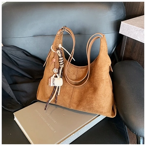 Détail de la texture du sac hobo en daim marron avec un pendentif café sur une chaise