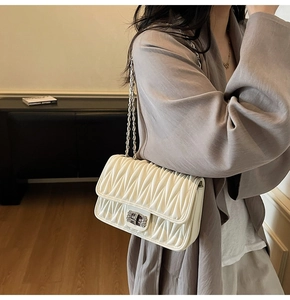 Detailansicht der weißen Stepptasche mit Silberkette und Metallverschluss von der Seite