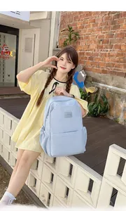 Detail view of light blue fashion backpack with side pockets and woven label on front