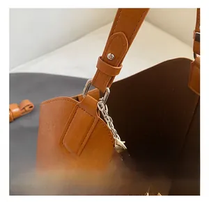 Close-up of brown PU leather bucket bag with silver hardware and woven handle detail