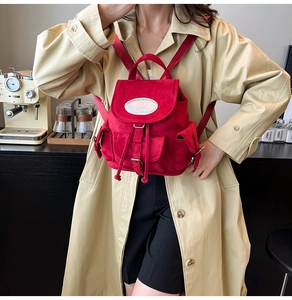 Détail d'un sac à dos en daim rouge avec cordon de serrage et boucle sur le rabat