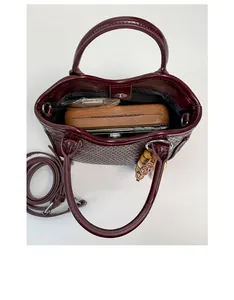 Vue intérieure montrant la capacité du sac tressé bordeaux avec téléphone et objets