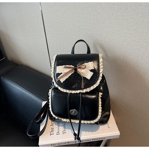 Détail d'un sac à dos noir vintage avec bordure en dentelle blanche et nœud décoratif