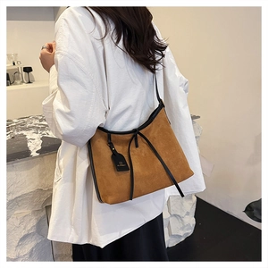 Close-up of brown suede tote bag with black leather trim and hanging brand tag