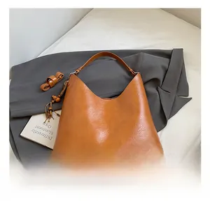 Close-up of brown PU leather bucket bag with lychee texture and wooden bead tassel