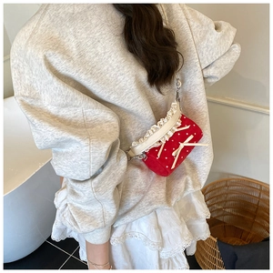 Primer plano de bolso bandolera rojo de lunares con bordes de encaje y detalle de lazo
