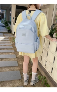 Detail of light blue waterproof nylon backpack with leather logo patch and drawstring pocket