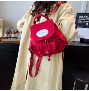 Détail du sac à dos en daim rouge avec boucle métallique et poches latérales sur manteau