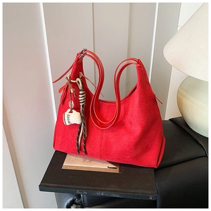 Détail d'un sac hobo rouge en daim avec bandoulière réglable et breloque café