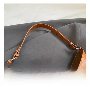 Detail of brown leather bucket bag showing adjustable metal buckle and chain handle texture