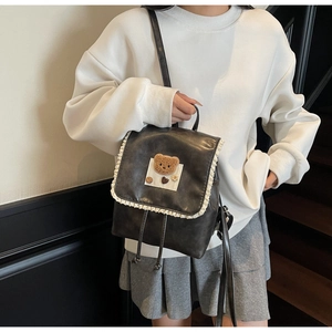 Black leather backpack with lace trim and bear embroidery shown on a model