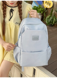 Close-up of light blue nylon backpack showing the texture and brand label in detail